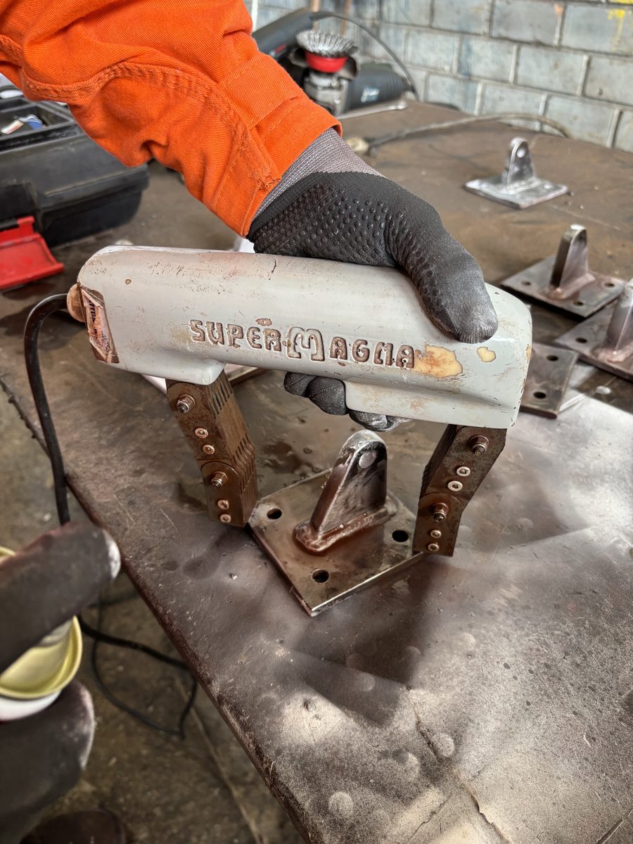 Ensaio por partículas magnéticas com yoke na solda da base de um suporte da linha de vida